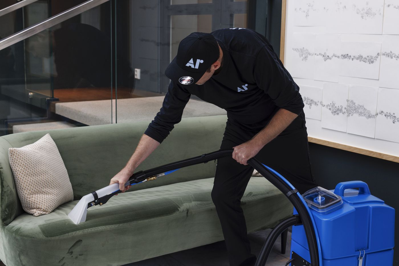 Renholder rengjør en sofa med tekstilrensemaskin.